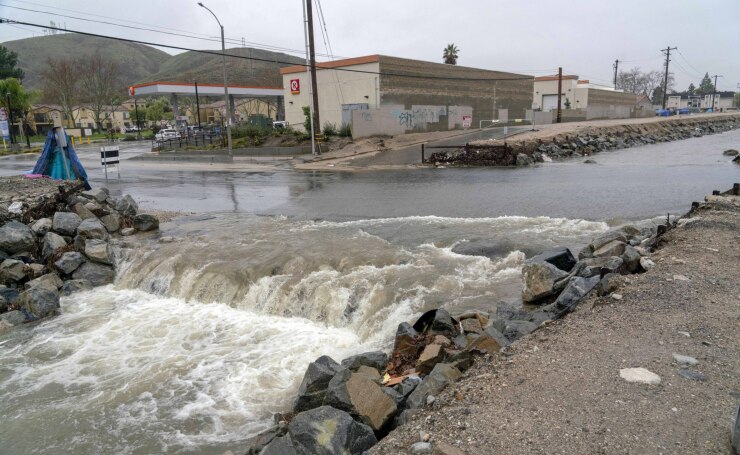 Floodwaters rush over a closed road Feb. 6, 2024, in San Bernardino, California.
